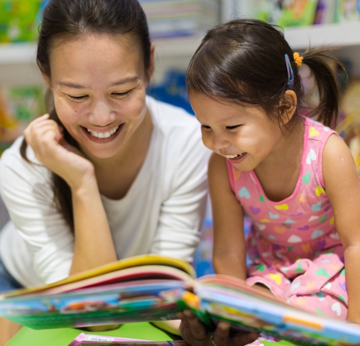 mom and young daughter looking at picture book